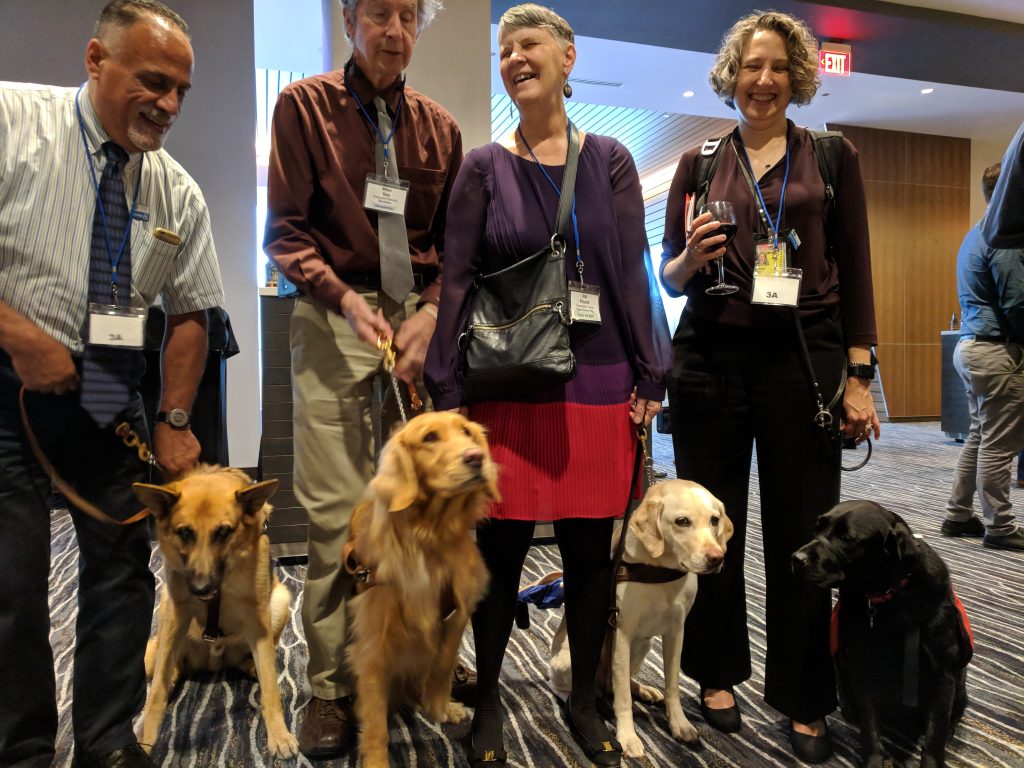 A photo including 4 attendees who are blind or low-vision with their service animals